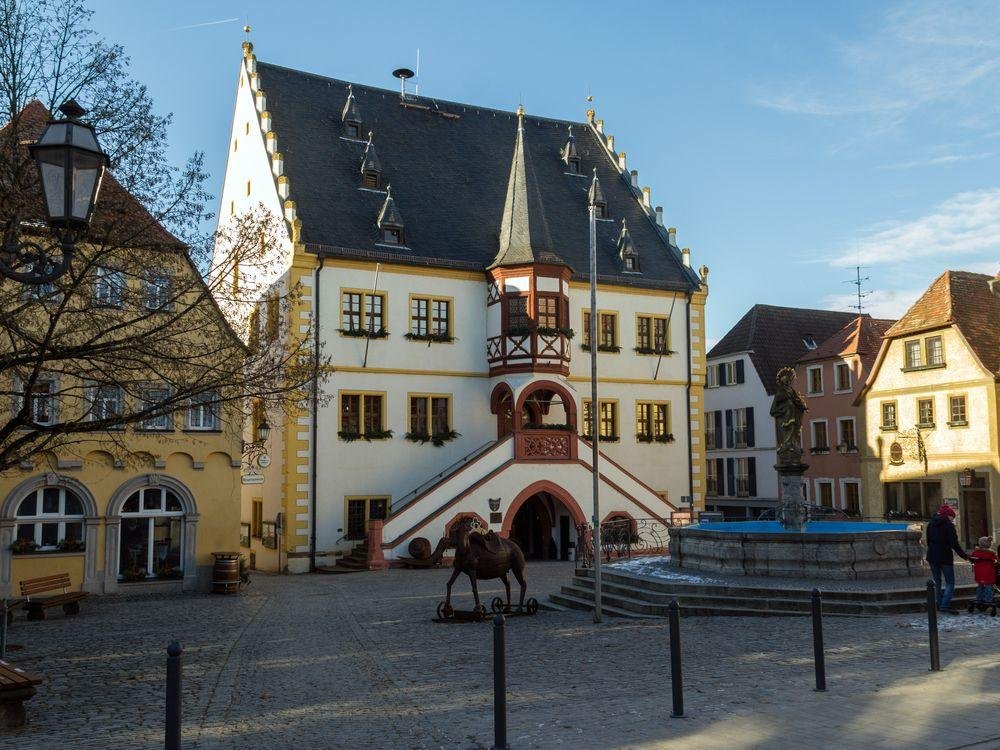 Marktplatz von Volkach mit dem weiß-gelben Rathaus, seiner roten Freitreppe und dem Marktbrunnen im Nachmittagslicht